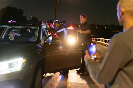 Shot of a police officer arresting a driver he pulled over at night